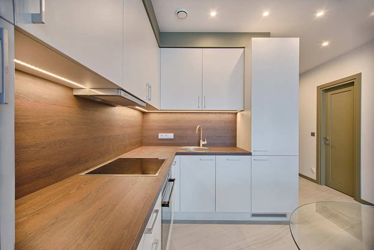 Affordable white modular kitchen with wood-grain countertop and under-cabinet LED lighting Rajkot