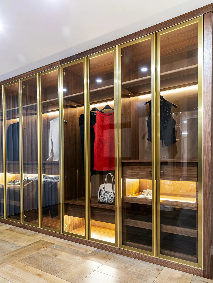 Luxury modular glass-door wardrobe with brass-finish profiles and warm LED interior lighting in Rajkot